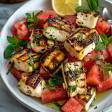 A plate of food with watermelon, lemon, and mint.