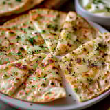A slice of pizza with cheese and herbs.