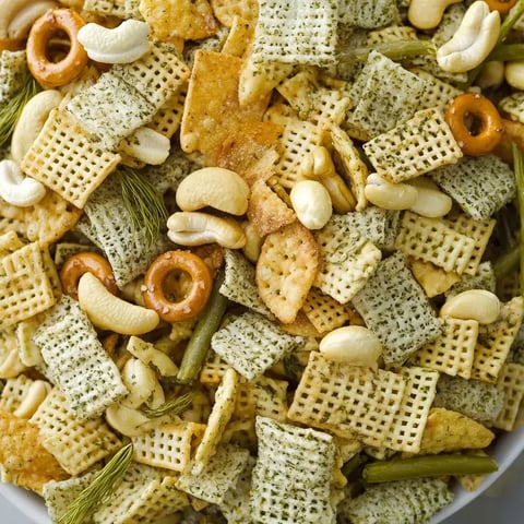 A colorful assortment of snack mix featuring crunchy cereal pieces, pretzel rings, and various nuts.