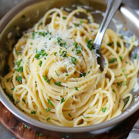 A bowl of pasta with cheese and herbs.